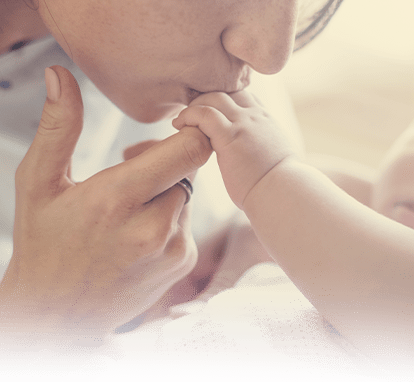 A mother kisses her baby's tiny hands.