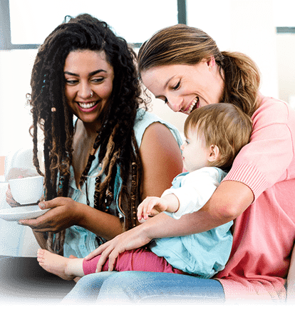 Two smiling woman with a child.