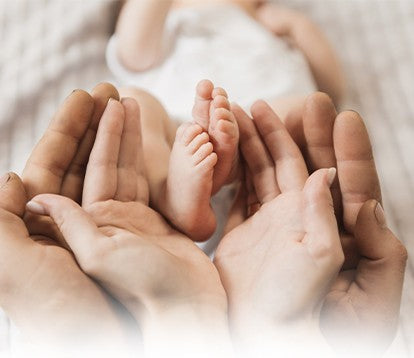 Parents' hands holding a baby's feet.