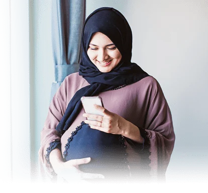 A pregnant woman happily looking at her phone.