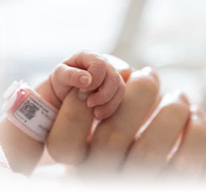 A baby holds its mother's finger.