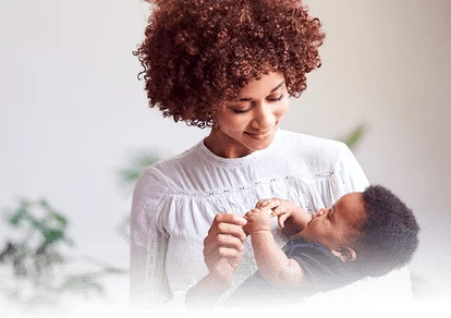 A mother embraces her baby, smiling.