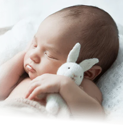 A baby sleeping with a rabbit toy.