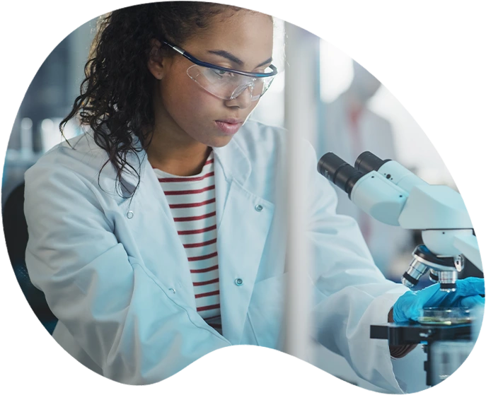 A woman looks at a sample through a microscope.