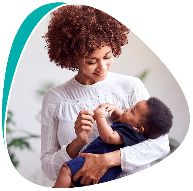 A mother embraces her baby, smiling.